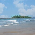 a sandy beach with a small island in the distance