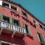 a red building with green shutters and a plane flying in the sky