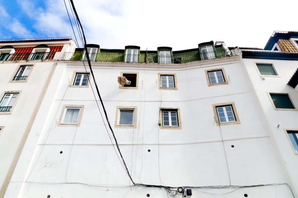 a tall white building with windows and a sky background