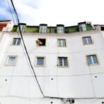 a tall white building with windows and a sky background