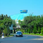 a car driving down a street next to a tall building