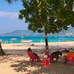 A group of people sitting on top of a sandy beach